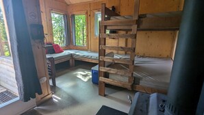 A cabin with bunk beds, a desk, and a window overlooking greenery. - Perched lakeside treehouse, suspension bridge and deck | Lodging #16 (Mont-Blanc)