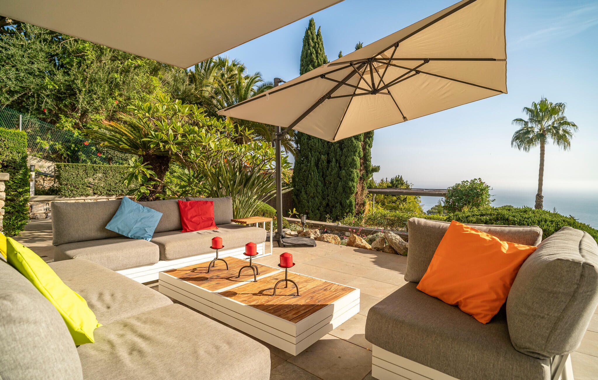 Un espace extérieur aménagé avec un canapé, une table basse et un grand parasol.