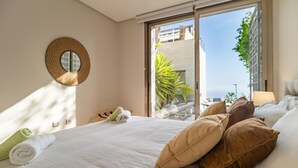 Hotellihuone, jossa on sänky, tyynyjä, pyöreä peili ja näkymä ulos.