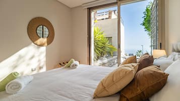 Habitación de hotel con cama, almohadas, un espejo redondo y vistas al exterior.