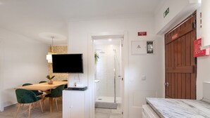 Habitació d'hotel amb zona de menjador, televisió, dutxa i porta de fusta.