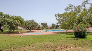 Zona de piscines amb diverses piscines, envoltada d'herba i arbres.