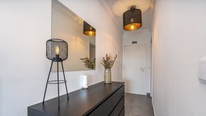 Une salle de bain moderne avec un plan de toilette foncé, un miroir, un vase de fleurs et deux lampes suspendues.