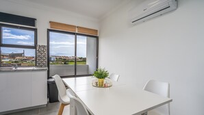 Une cuisine moderne avec une table à manger, des chaises, une plante en pot et une vue sur le paysage urbain.