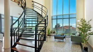 A spacious living area with a curved staircase, large windows, and a view of the outdoors. - Holiday Home 'Pico Do Paraíso' with Sea View, Wi-Fi and Air Conditioning (Funchal)