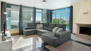 A modern living room with a sectional sofa, a fireplace, and large windows. - Holiday Home 'Pico Do Paraíso' with Sea View, Wi-Fi and Air Conditioning (Funchal)