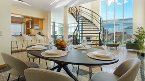 A dining area with a round table set for four, a spiral staircase, and a view of the outdoors. - Holiday Home 'Pico Do Paraíso' with Sea View, Wi-Fi and Air Conditioning (Funchal)