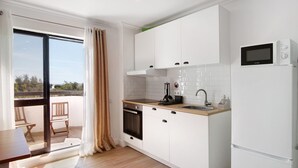A modern kitchen with white cabinets, a built-in oven, a microwave, and a sink.