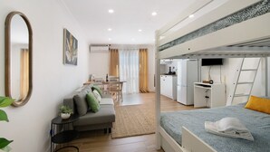 A compact, modern apartment with a bunk bed, a kitchenette, a dining area, and a living space.