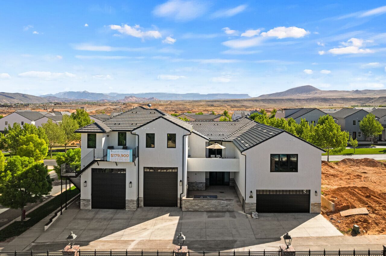 Une maison moderne à deux étages, dotée d’un garage, d’un patio couvert et offrant une vue sur un paysage désertique.