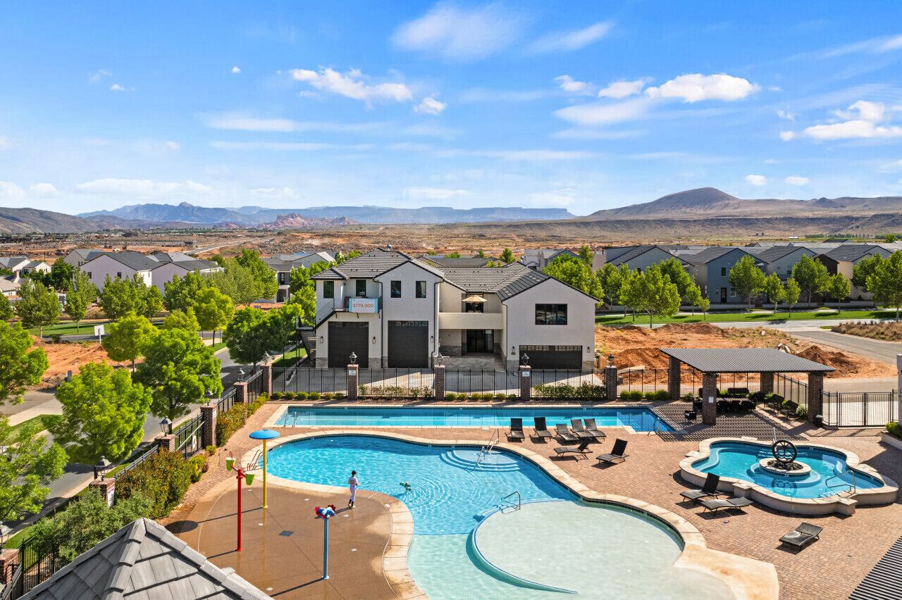 A residential area with a swimming pool, multiple houses, and a mountainous backdrop.