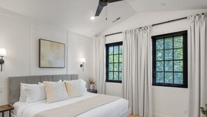 A bedroom with a large bed, two windows with curtains, a ceiling fan, and a wall-mounted light fixture. - Our Place; Our Home has an inside slide, gourmet kitchen, view for days, and just feels like home! (Hurricane)