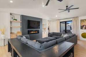 Ein modernes Wohnzimmer mit einem Ecksofa, einem Flachbildfernseher und einem Kamin.