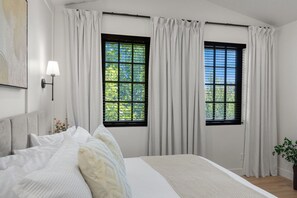 A bedroom with a bed, two windows with curtains, a bedside lamp, and a wall-mounted artwork. - Our Place; Our Home has an inside slide, gourmet kitchen, view for days, and just feels like home! (Hurricane)