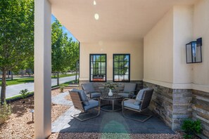 A covered patio area with outdoor seating, a stone wall, and a view of a street and trees. - Our Place; Our Home has an inside slide, gourmet kitchen, view for days, and just feels like home! (Hurricane)