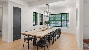 A modern dining area with a long wooden table, black chairs, and a potted plant. - Our Place; Our Home has an inside slide, gourmet kitchen, view for days, and just feels like home! (Hurricane)