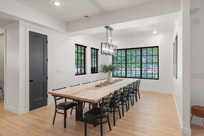 A modern dining area with a long wooden table, black chairs, and a potted plant. - Our Place; Our Home has an inside slide, gourmet kitchen, view for days, and just feels like home! (Hurricane)