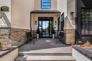 A building entrance with a stone facade, a black door, and two potted plants. - Our Place; Our Home has an inside slide, gourmet kitchen, view for days, and just feels like home! (Hurricane)