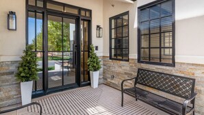 A building entrance with a glass door, a bench, and two potted plants. - Our Place; Our Home has an inside slide, gourmet kitchen, view for days, and just feels like home! (Hurricane)