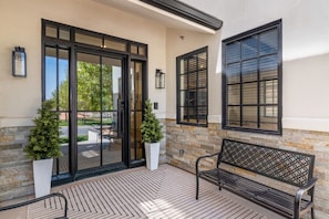 A building entrance with a glass door, a bench, and two potted plants. - Our Place; Our Home has an inside slide, gourmet kitchen, view for days, and just feels like home! (Hurricane)