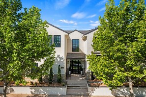 A modern two-story house with a white exterior, a dark roof, and a front entrance with steps leading up to a door. - Our Place; Our Home has an inside slide, gourmet kitchen, view for days, and just feels like home! (Hurricane)