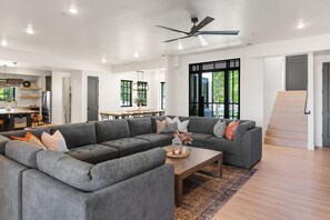 A spacious living area with a large grey sectional sofa, a wooden coffee table, and a ceiling fan. - Our Place; Our Home has an inside slide, gourmet kitchen, view for days, and just feels like home! (Hurricane)