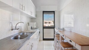 A modern kitchen with a stainless steel sink, white cabinets, and a wooden countertop. - Apartment 'City Center' with Balcony, Wi-Fi and Air Conditioning (Albufeira)