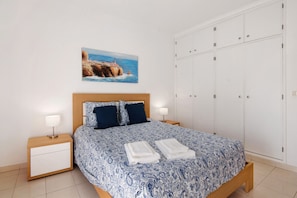 A bedroom with a bed, two bedside tables, a wardrobe, and a painting on the wall.