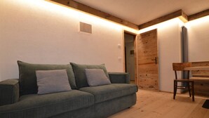 Un salon chaleureux avec un canapé vert, une porte en bois et un radiateur.