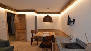 Une cuisine de taille réduite, avec une table en bois, des chaises, un luminaire suspendu et une cuisinière intégrée.