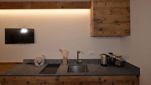 Une cuisine moderne équipée d’un téléviseur encastré, d’un meuble en bois, d’un évier et d’un plan de travail.