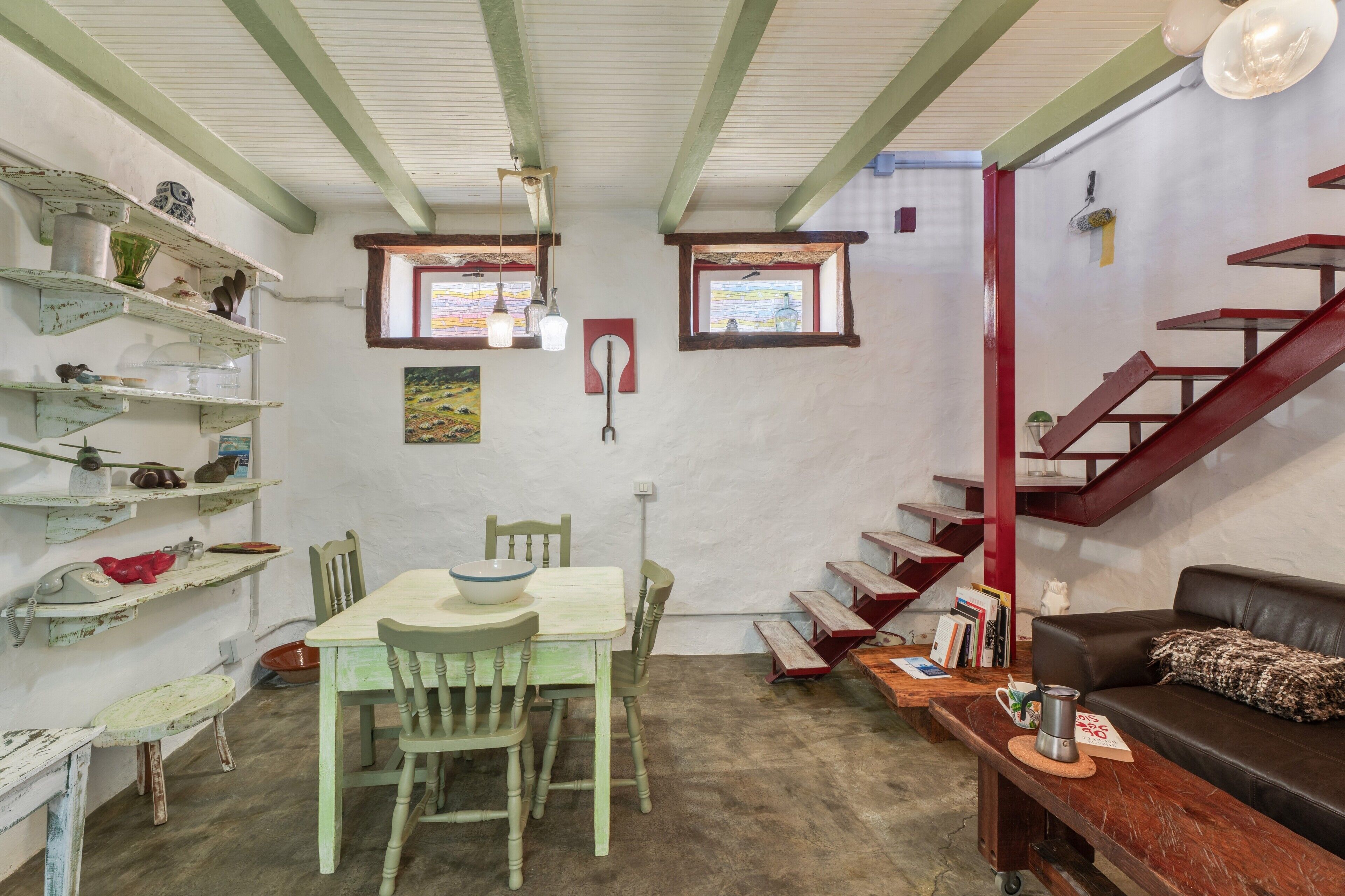 A dining area with a table and chairs, a staircase, and a sofa.