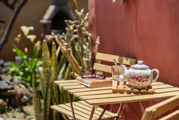 A wooden table with a teapot, a book, and glasses.