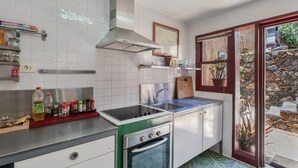 Una cocina con paredes de azulejos blancos, electrodomésticos de acero inoxidable y una pared de piedra en el exterior.