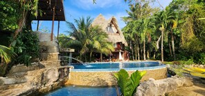 A tropical resort with a swimming pool, thatched-roof cottages, and lush greenery. - CASA CARIBE HOTEL (Livingston)