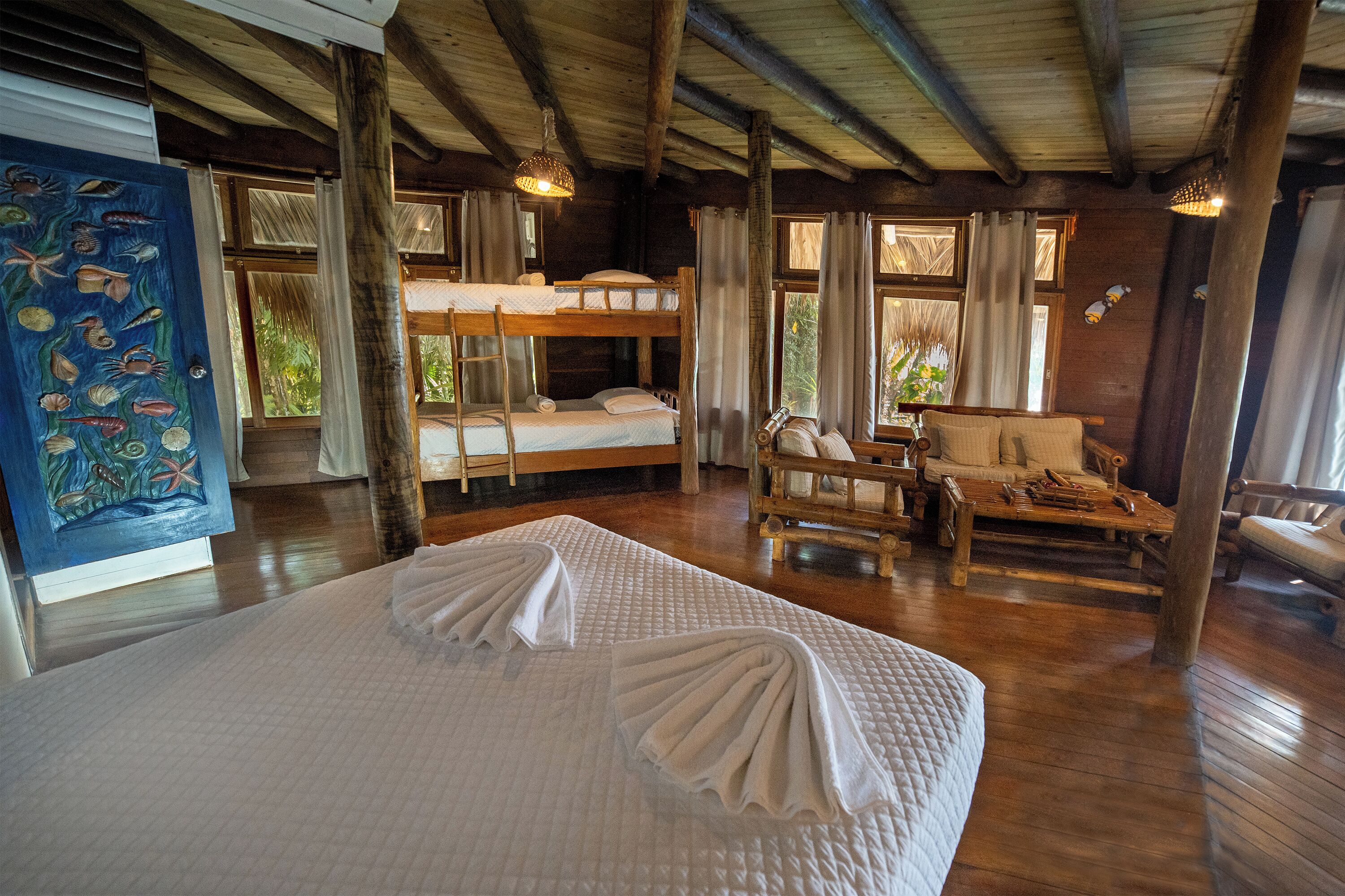 A room with bunk beds, a wooden table, and a painting of fish.