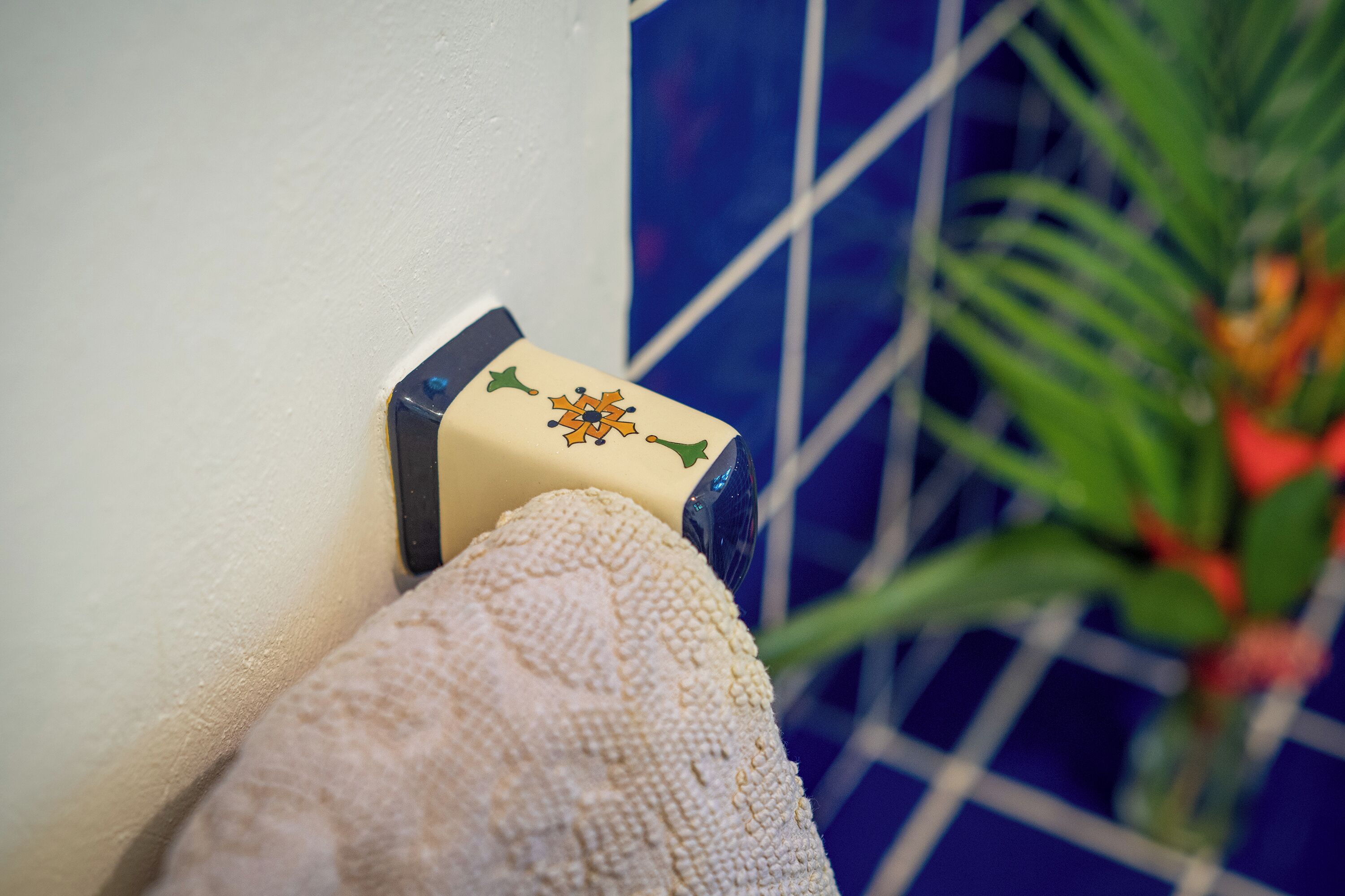 A textured wall corner with a decorative object, a tiled wall, and a plant in the background.