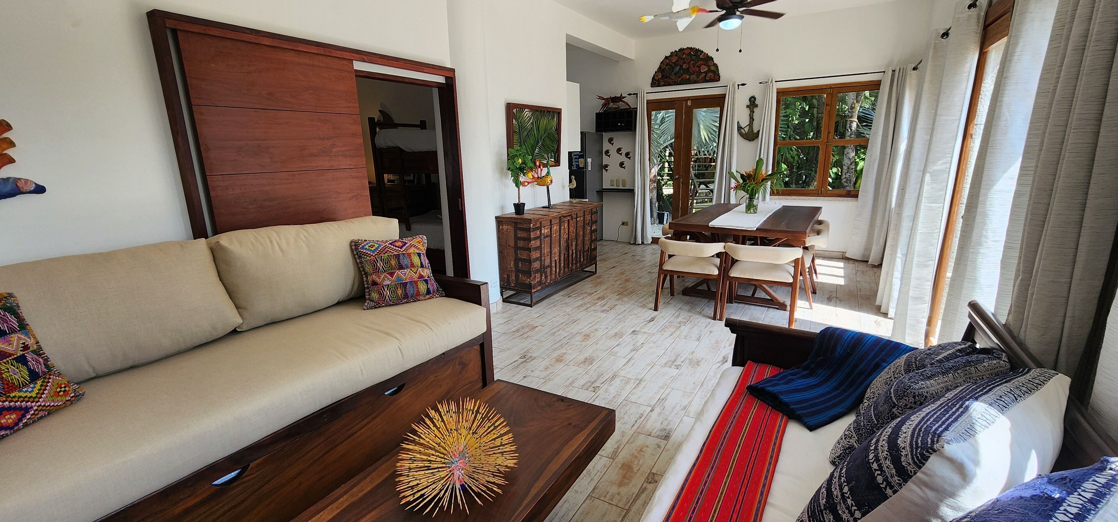 A living room with a sofa, coffee table, and a dining area with a table and chairs.