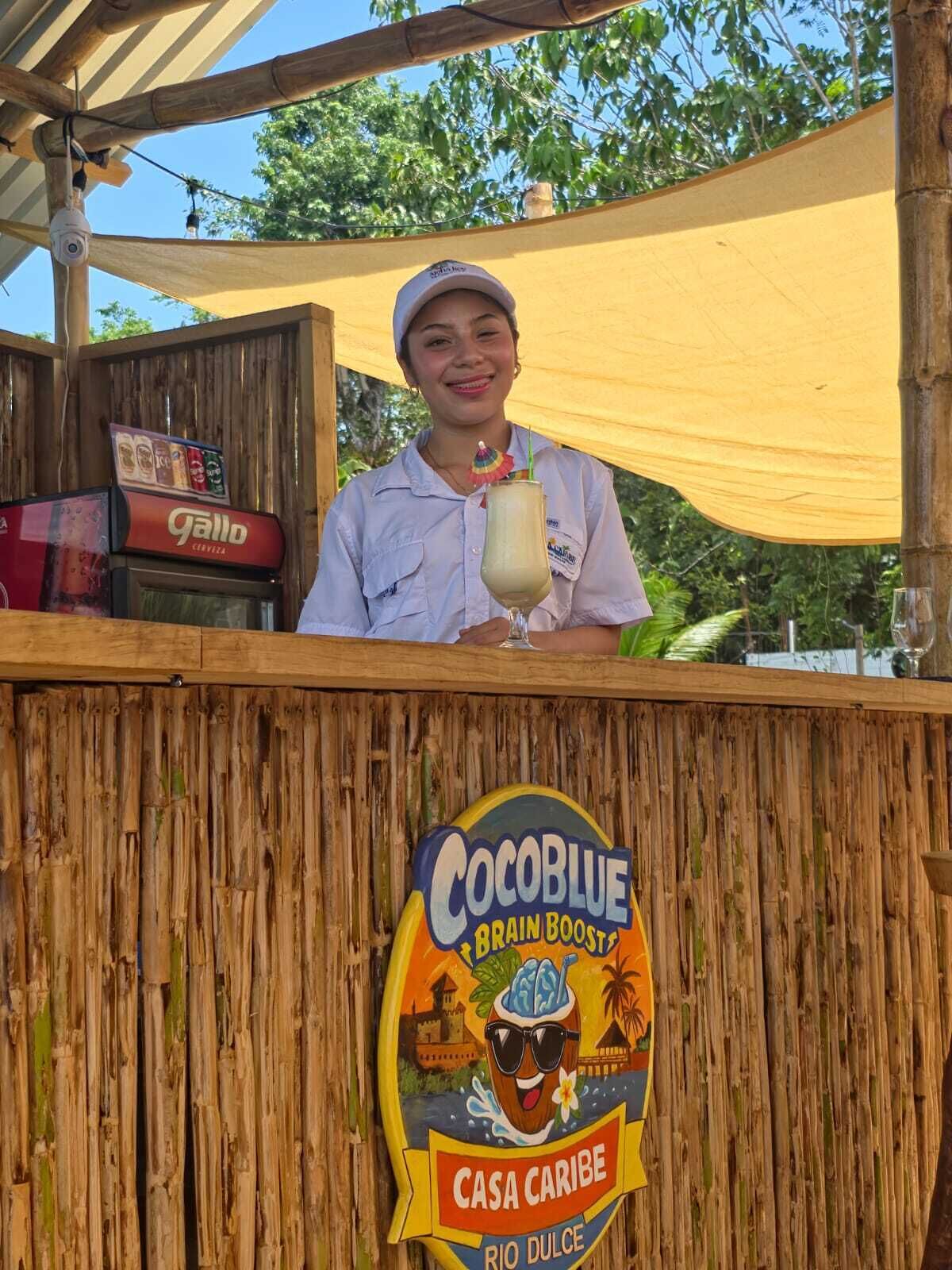 A person behind a wooden counter with a sign for Cocoblu Brain Boosts.