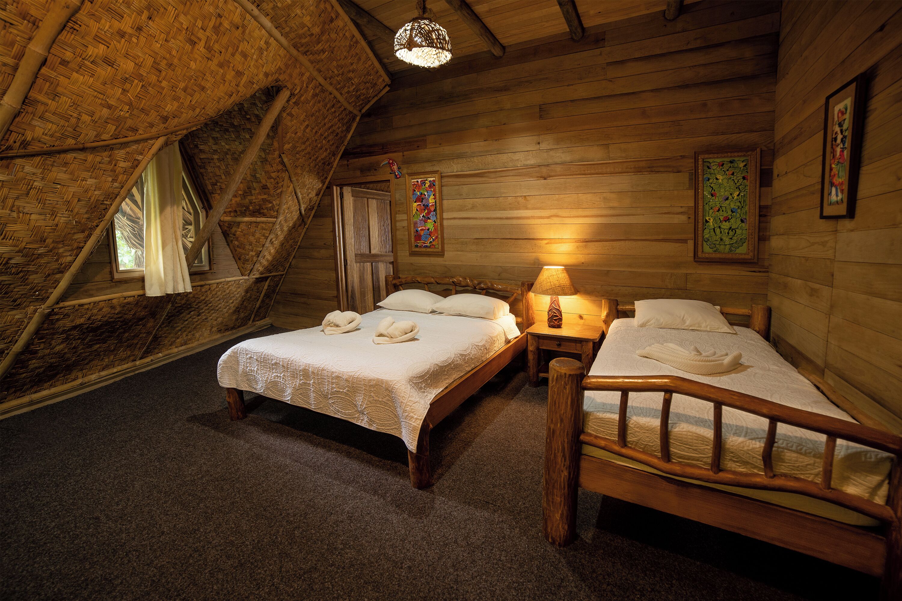 A cozy room with two beds, a wooden ceiling, and a small window.