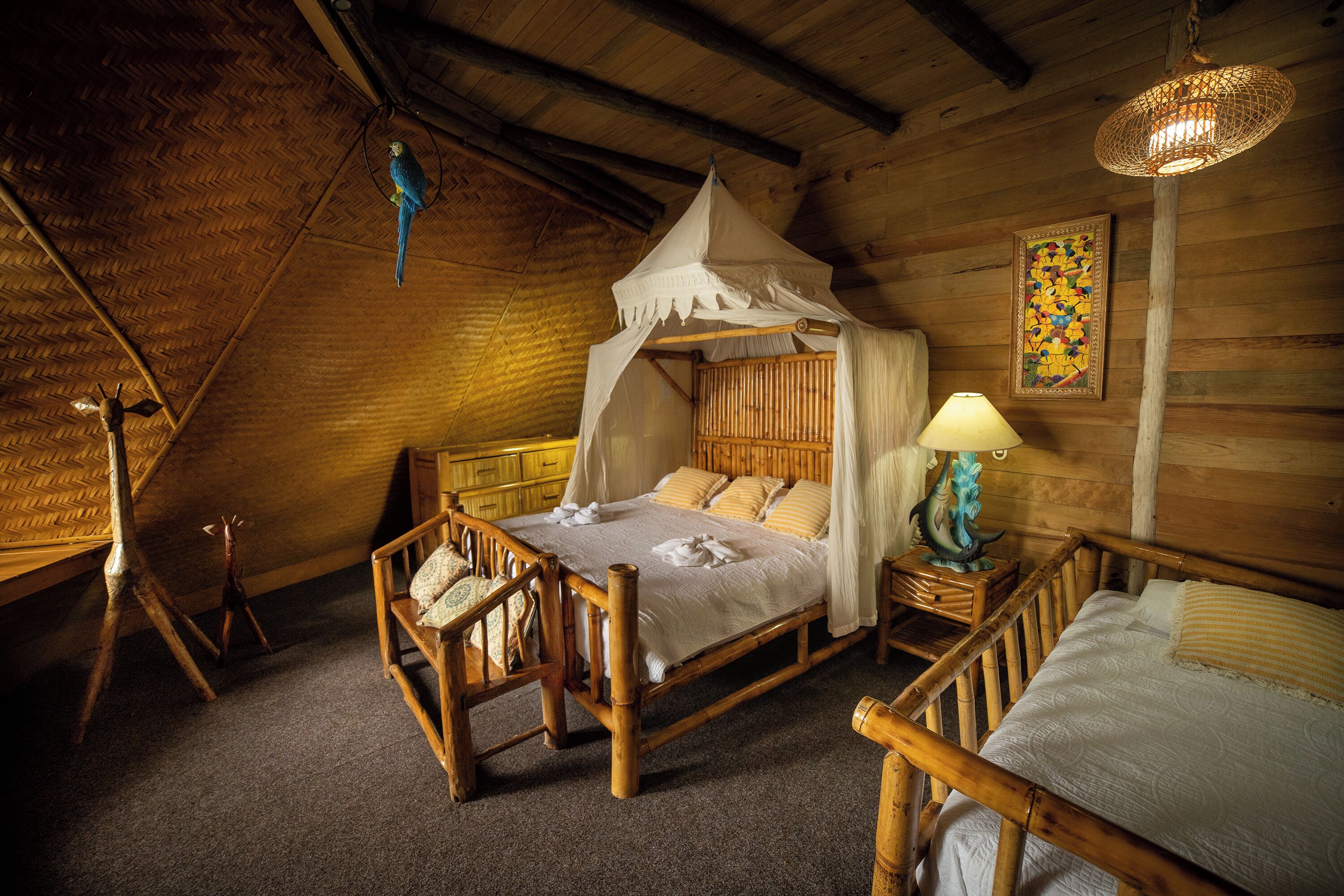 Ein Zimmer aus Holz mit einem Bett, einem Nachttisch, einem Stuhl, einem hängenden Vogelkäfig und einer Wandlampe.