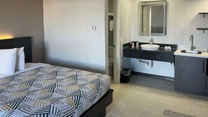 A hotel room with a bed, a bathroom with a sink, and a mirror.