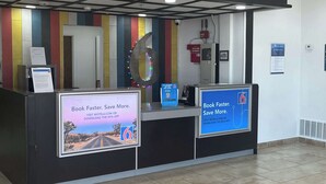 A reception desk with a large number '6' sign, a QR code, and a sign promoting a mobile app.