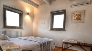 A bedroom with a bed, bedside table, and a small table with towels. There are two windows and a radiator. - Design Loft Apartment (Marsciano)