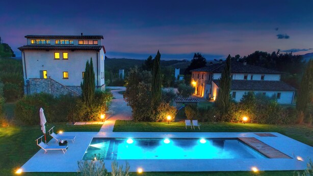 A modern house with a swimming pool, outdoor seating, and a well-lit garden at dusk. - Exclusive farmhouse with heated swimming pool (Marsciano)