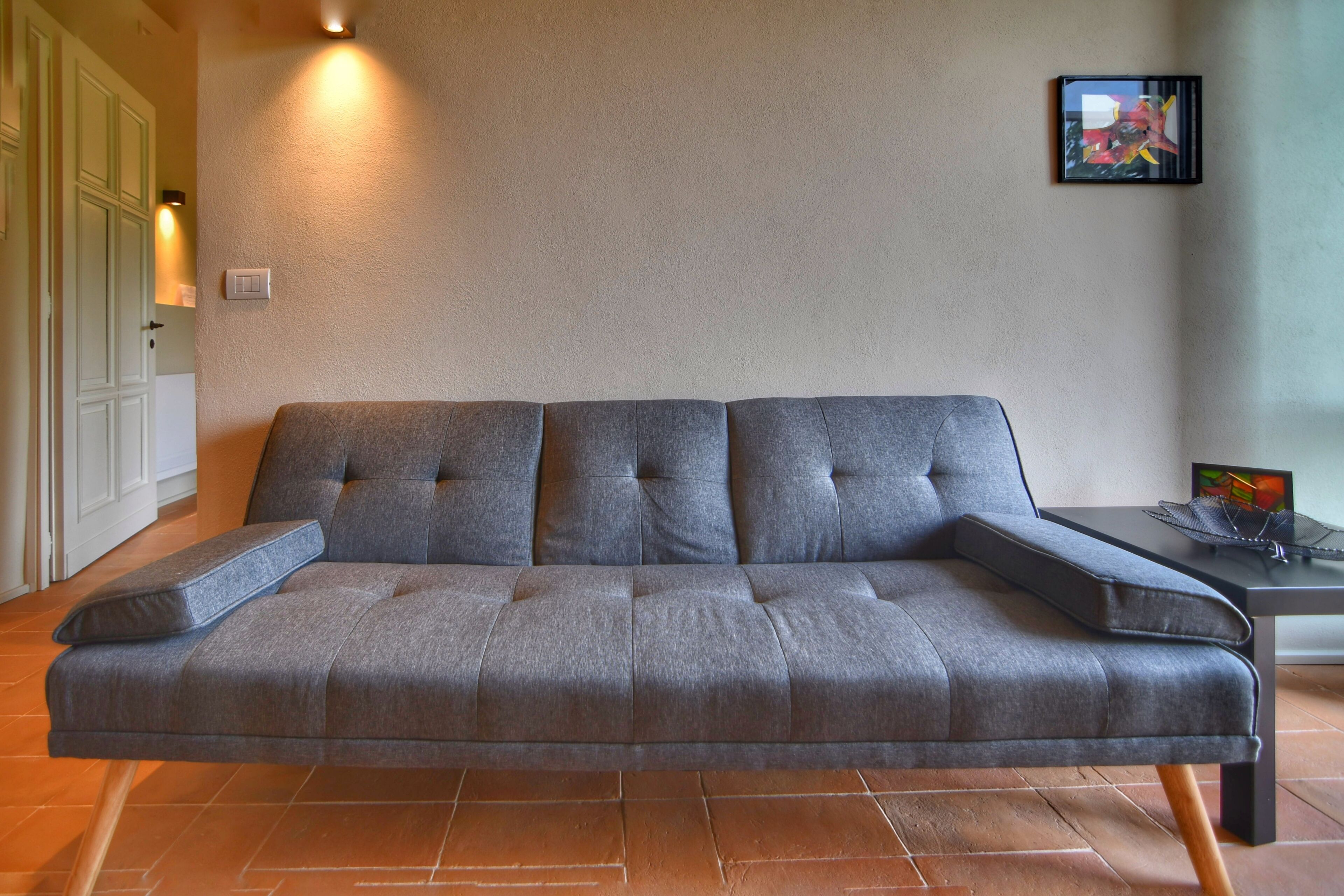 A modern sofa with a padded headrest and armrests, positioned on a tiled floor.