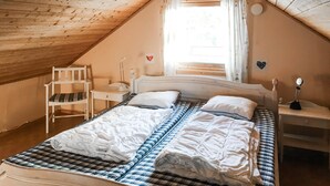 A small, cozy attic bedroom with a sloped ceiling, a single bed with a checkered bedspread, a bedside table with a lamp, and a chair. - Amazing apartment in Idre with sauna (Idre)