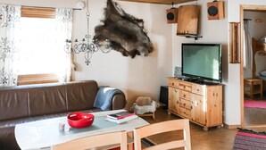 A living room with a brown sofa, a wooden cabinet, a television, and a chandelier. - Amazing apartment in Idre with sauna (Idre)