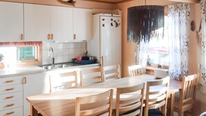 A kitchen with white cabinets, a sink, and a refrigerator. There are wooden chairs and a table. - Amazing apartment in Idre with sauna (Idre)