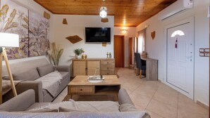 A living room with a wooden ceiling, a flat-screen TV mounted on the wall, a sofa, a coffee table, and a cabinet. - Private Pool, Sunny Location, South Rethimno, Ideal for Adults (Saktouria)